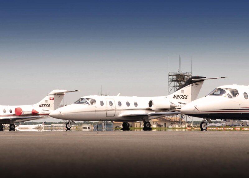 Fleet of Private jets on runway in front of tower